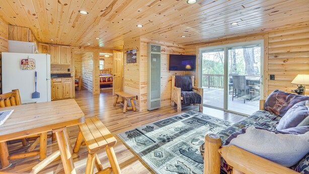 A wooden cabin interior with a dining area, a sofa, and a television. - Lakefront Cabin w/ Dock, Fire Pits in Danbury! (Danbury)
