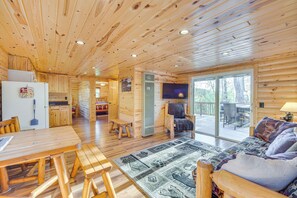 A wooden cabin interior with a dining area, a sofa, and a television. - Lakefront Cabin w/ Dock, Fire Pits in Danbury! (Danbury)