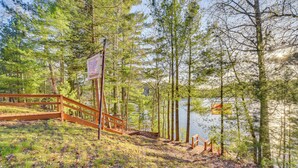 A wooden deck leading to a lake surrounded by trees. - Lakefront Cabin w/ Dock, Fire Pits in Danbury! (Danbury)