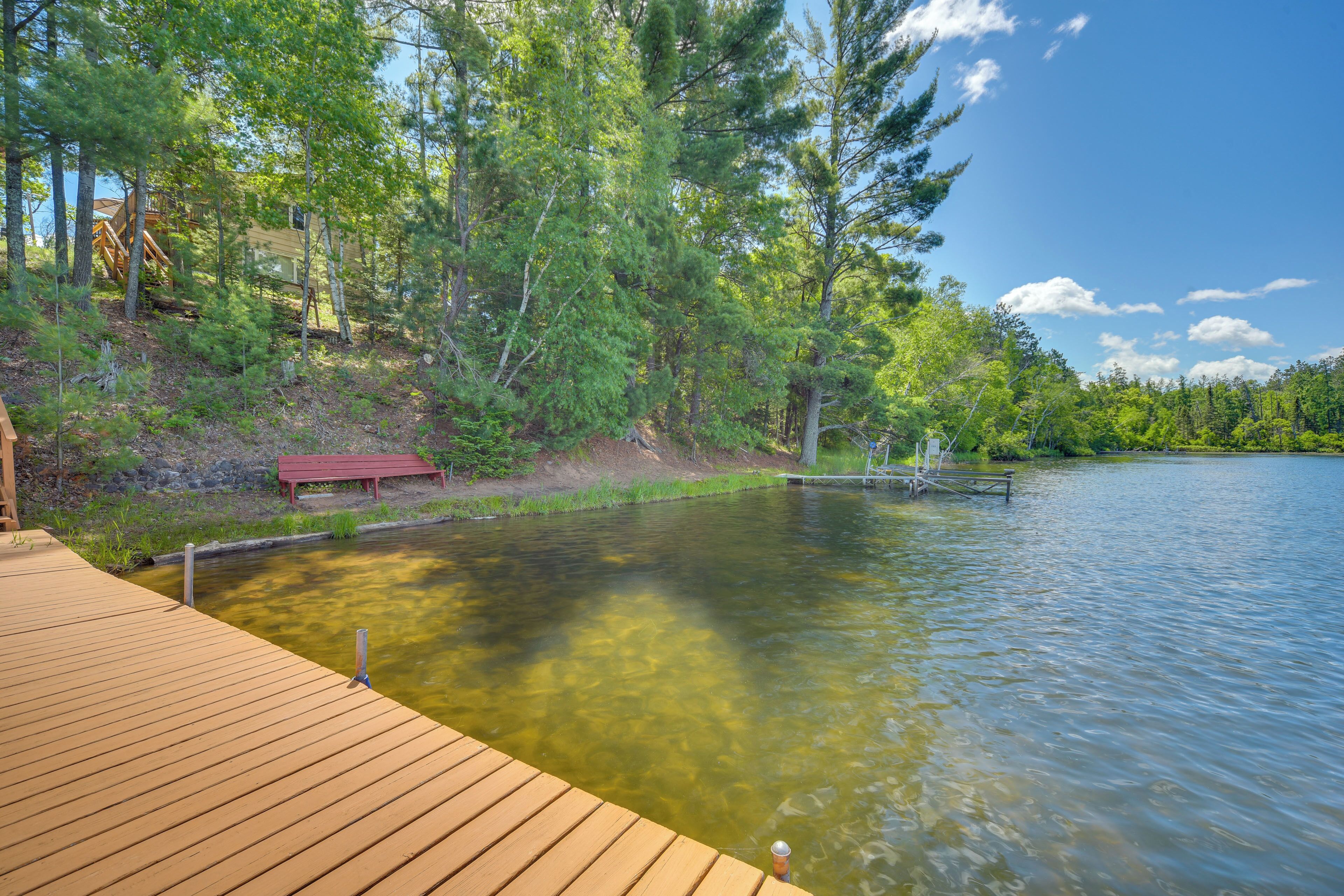 Une terrasse en bois qui mène à un lac paisible, entouré d’arbres.