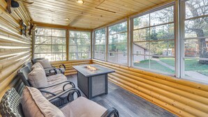 A log cabin interior with a fireplace, seating area, and large windows. - Lakefront Cabin w/ Dock, Fire Pits in Danbury! (Danbury)