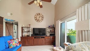 A living room with a sofa, a coffee table, a TV, and a wooden cabinet. - Mara Laguna Condo San Pedro Belize (San Pedro)