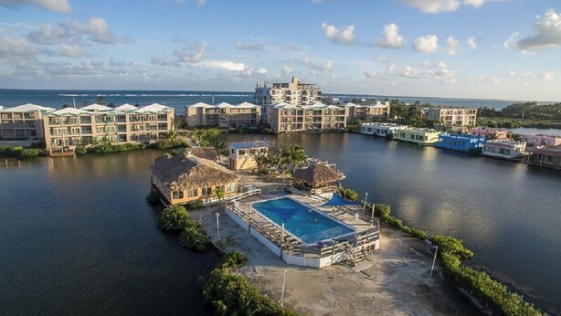 A resort with a central pool, multiple buildings, and a view of the ocean. - Mara Laguna Condo San Pedro Belize (San Pedro)
