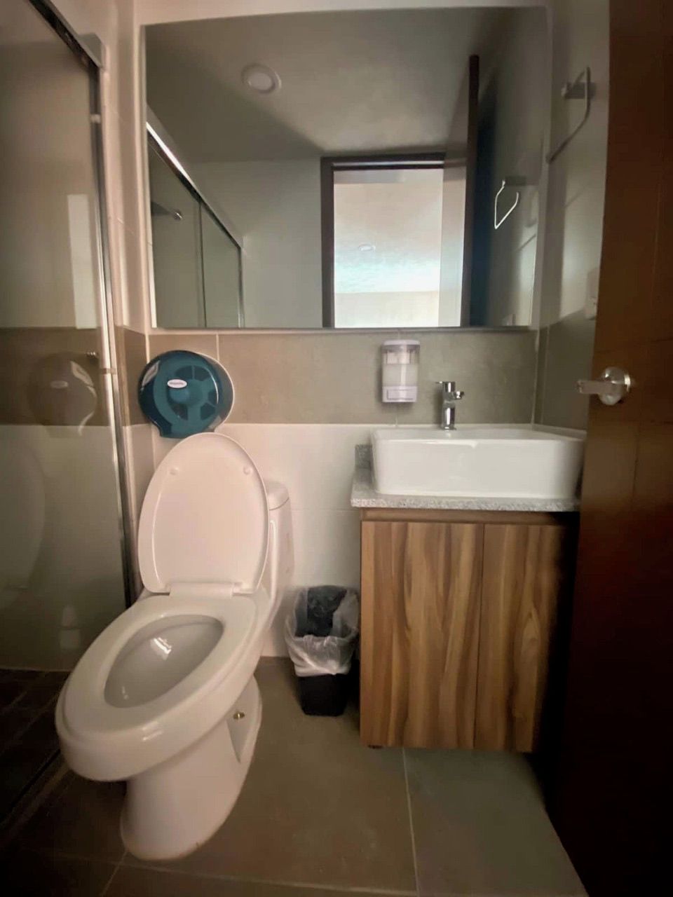 A bathroom with a toilet, sink, and mirror.