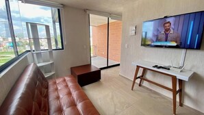 A modern living room with a leather sofa, a TV mounted on the wall, and a sliding glass door leading to an outdoor area. - Torre San Francisco Zoológico 132 (Guadalajara)
