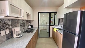 A compact kitchen with a microwave, coffee maker, stove, and refrigerator. - Torre San Francisco Zoológico 132 (Guadalajara)