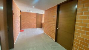 A corridor with brick walls and numbered doors, leading to individual rooms. - Torre San Francisco Zoológico 132 (Guadalajara)