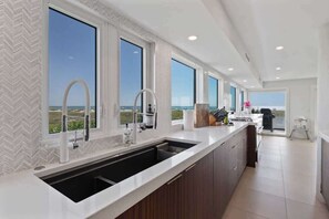 Una cucina moderna con ampie finestre, un lavello incassato e vista sull'oceano.