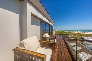 Un balcone con posti a sedere all'aperto e vista sulla spiaggia.