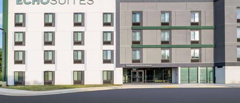 A modern hotel building named ECHOSUITES with a clean, rectangular facade, multiple windows, and a sign indicating extended stay by Wyndham.