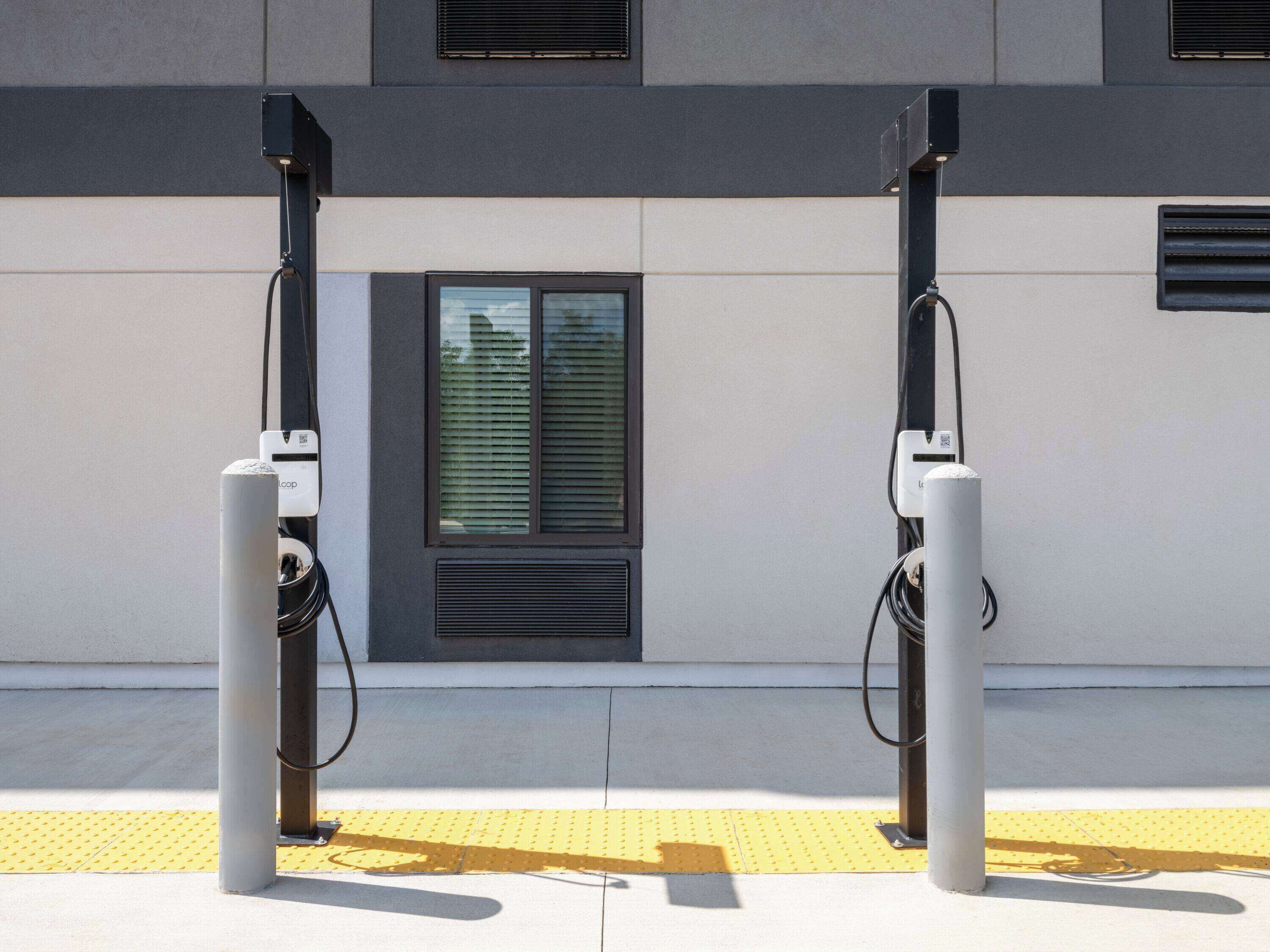 Deux bornes de recharge pour véhicules électriques fixées sur la façade d’un bâtiment.