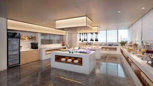 Un hall d’hôtel moderne doté d’un îlot central, d’un espace dédié au café et d’un réfrigérateur.