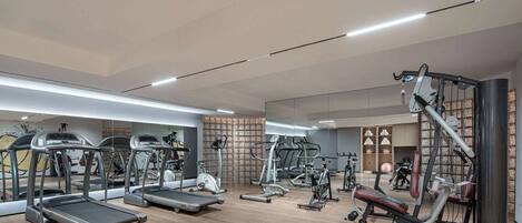 A modern gym with treadmills, elliptical machines, and weight equipment.