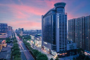 A modern high-rise hotel with a distinctive curved top and multiple floors. - Microtel By Wyndham Handan New Century (Handan)