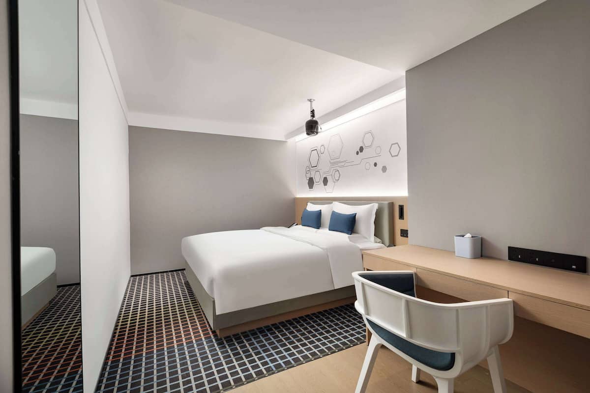 Una habitación de hotel moderna con una cama bien hecha, un escritorio y una silla.