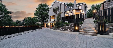 A modern two-story house with a paved driveway and a landscaped garden.