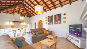A modern living room with a wooden ceiling, a sofa set, a dining table, and a television. - Cubo's La Luz del Valle Rural House / air conditioning / free wifi / BBQ / private pool (Alhaurín el Grande)