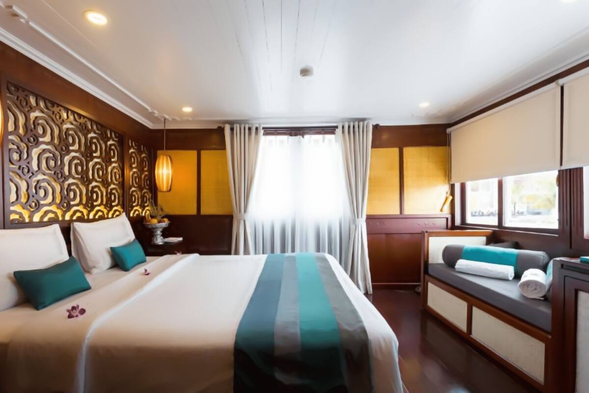 A hotel room with a large bed, a sofa, a desk, and a window with curtains.