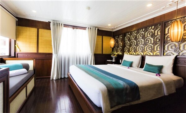 Una habitación de hotel con una cama grande, una cama más pequeña, un escritorio y una ventana con cortinas.