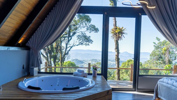 A modern spa room with a wooden hot tub, large windows, and a view of mountains. - Casa da Mata (Sao Bento do Sul)