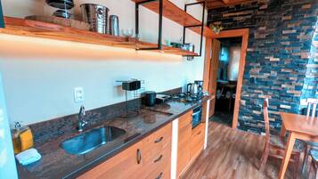 Une cuisine avec des meubles en bois, un plan de travail en granit et un porte-casseroles suspendu.