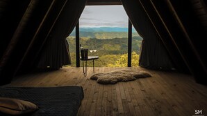 A cozy room with a wooden floor, a fur rug, and a table with a bottle and glasses. - Casa da Mata (Sao Bento do Sul)