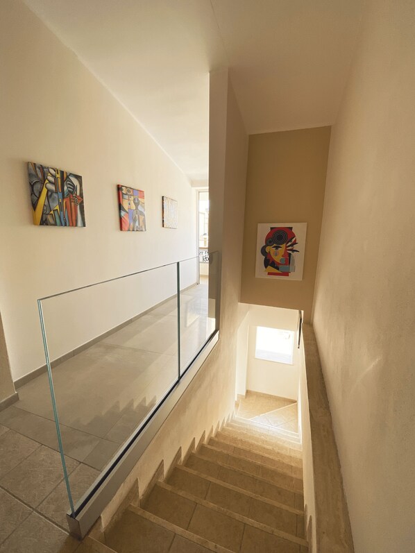 A modern interior with a glass railing, beige walls, and artwork. - Art Boutique Rooms (Isola di Capo Rizzuto)