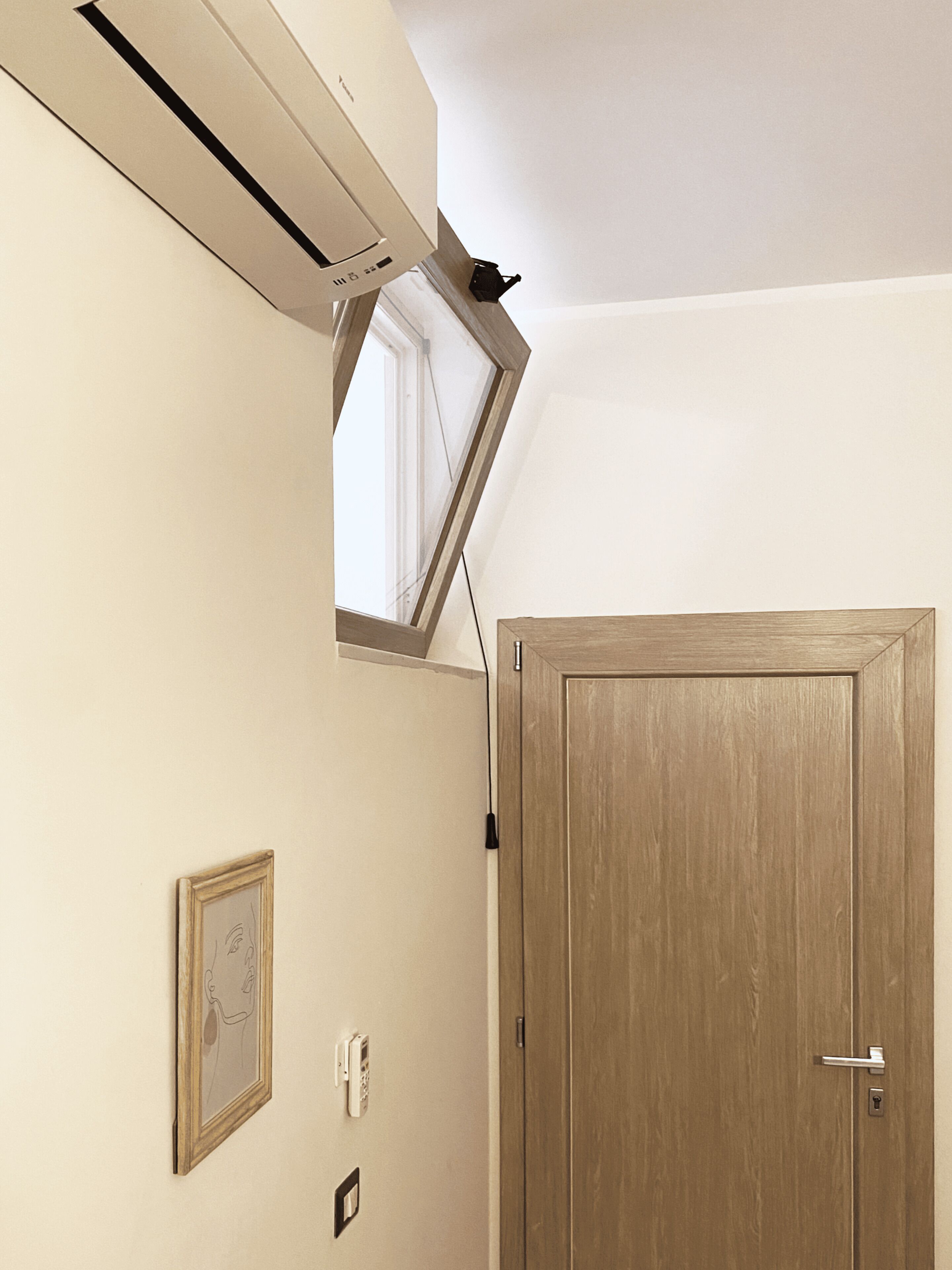 A room with a wooden door, a wall-mounted phone, and a framed picture.