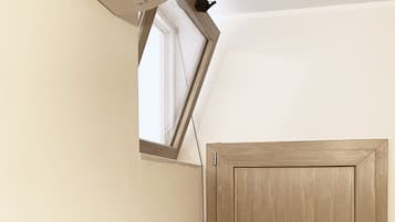 A room with a wooden door, a wall-mounted phone, and a framed picture.