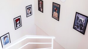 A staircase with a white handrail and a wall with framed artworks.