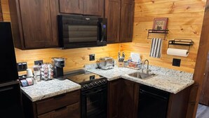 Cocina compacta con armarios de madera, microondas, estufa y fregadero.