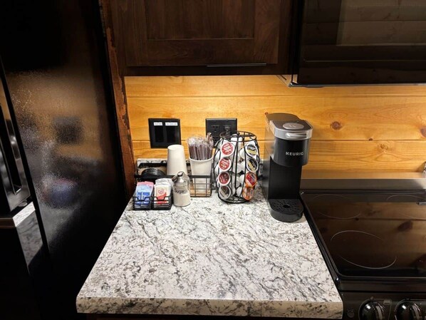 Una encimera de cocina con cafetera, azúcar, tazas de café y molinillo de café.