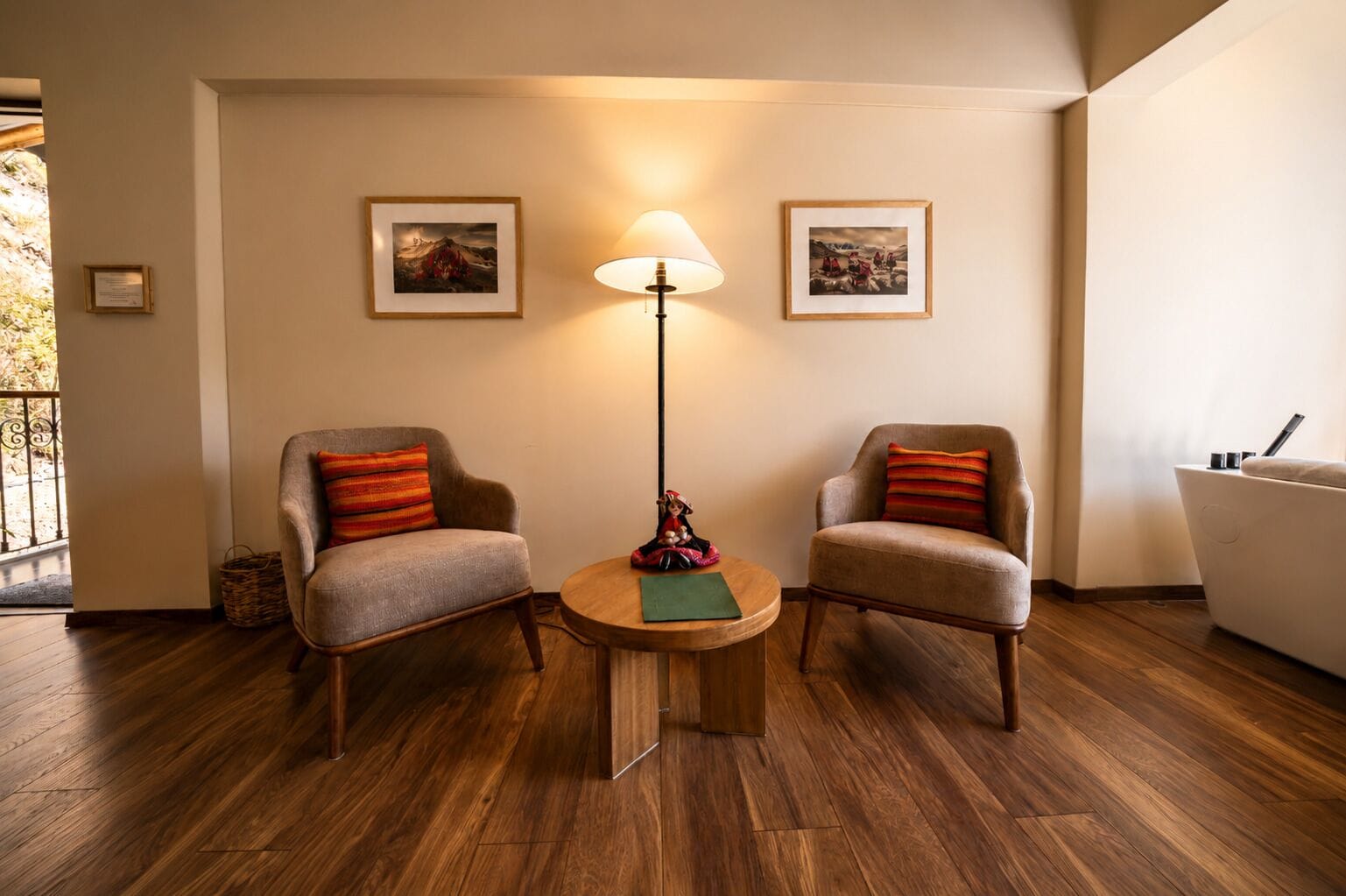 Une pièce comprenant deux fauteuils, une table ronde, un lampadaire et deux tableaux encadrés accrochés au mur.