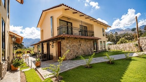 Una casa de dos pisos con fachada de piedra, un balcón y un césped bien cuidado.