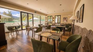 A dining area with tables and chairs, a stone wall, and a view of the outdoors.