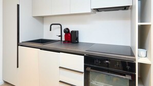 A modern kitchen with a black countertop, white cabinets, a built-in dishwasher, and a red coffee maker. - Black Water Bay house (Dubrovnik)