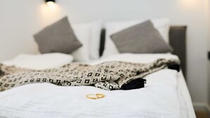 A neatly made bed with a patterned blanket, pillows, and a gold ring on the bedspread. - Black Water Bay house (Dubrovnik)