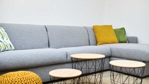 A grey sectional sofa with three round wooden tables and colorful cushions. - Black Water Bay house (Dubrovnik)