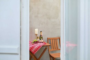 Ein kleiner Holztisch mit einer rot-weißen Tischdecke, zwei Champagnerflaschen, eine Kerze und ein Obstteller.