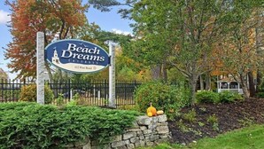 A sign for 'Beach Dreams Cottages' with a stone wall and autumn foliage in the background. - Charming Cottage for Rent at Beach Dreams Cottages, Wells, Maine! Unit #229 (Wells)