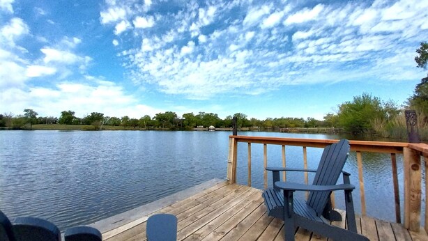 A wooden deck with a view of a lake and a cloudy sky. - Kansas Lake House With Private Boat Dock (Anthony)