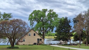 A two-story house with a large lawn and a dock extending into a lake. - Kansas Lake House With Private Boat Dock (Anthony)