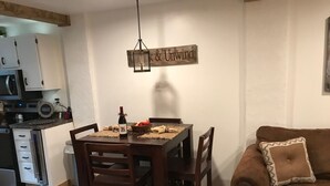 A dining area with a wooden table, chairs, and a hanging light fixture. - Cozy Condo (Cass)