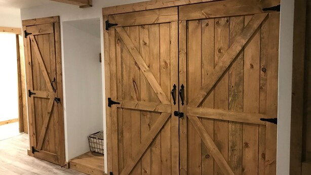 A room with two large wooden sliding doors, a light-colored wooden floor, and a small basket on the floor. - Cozy Condo (Cass)