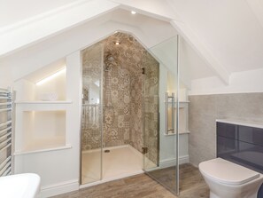 Ein modernes Badezimmer mit einer gläsernen Duschkabine, einer weißen Toilette und Holzboden.