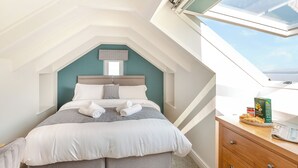 A bedroom with a skylight, a bed with pillows, a bedside table with a plate of croissants, and a magazine. - 3 bedroom accommodation in Llandanwg (Llandanwg)