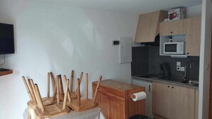Une cuisine compacte avec des meubles en bois, un four à micro-ondes et un petit coin repas comprenant une table et des chaises.