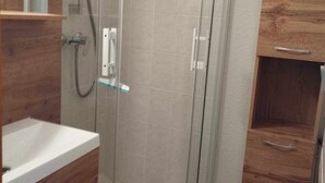 Une salle de bain avec une douche à parois de verre, un meuble-lavabo en bois et un miroir.