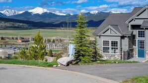 A house with a stone foundation, a blue door, and a view of snow-capped mountains in the background. - 6 Mi to Skiing: Mtn-View Fraser Duplex (Fraser)