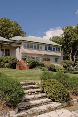 A two-story house with a well-maintained lawn and stone steps leading to the front door.